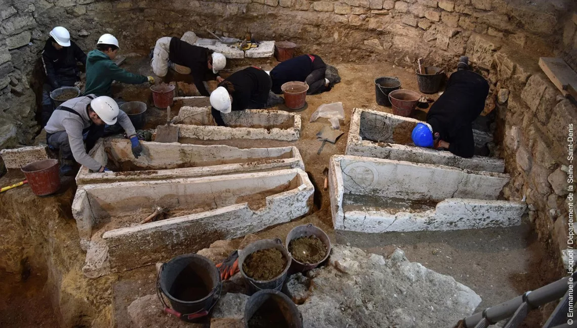 Fouille du massif occidental de Saint-Denis, intérieur, première travée nord, dégagement des squelettes déposés à l'intérieur des cuves de sarcophages mérovingiens (fin Ve-VIe siècle), mars 2023.
